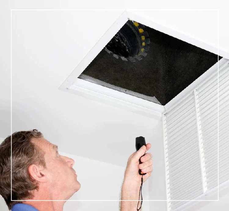 A man is looking at the ceiling vent.