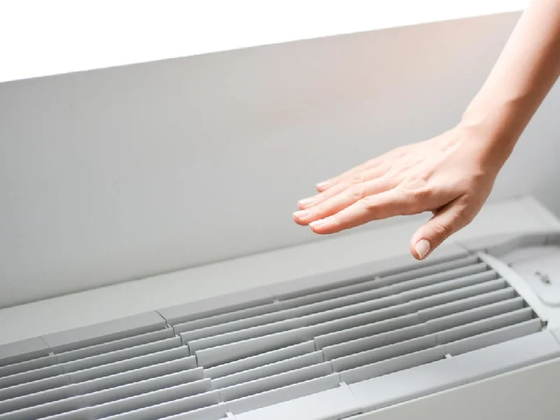 A person is reaching for the air vent.