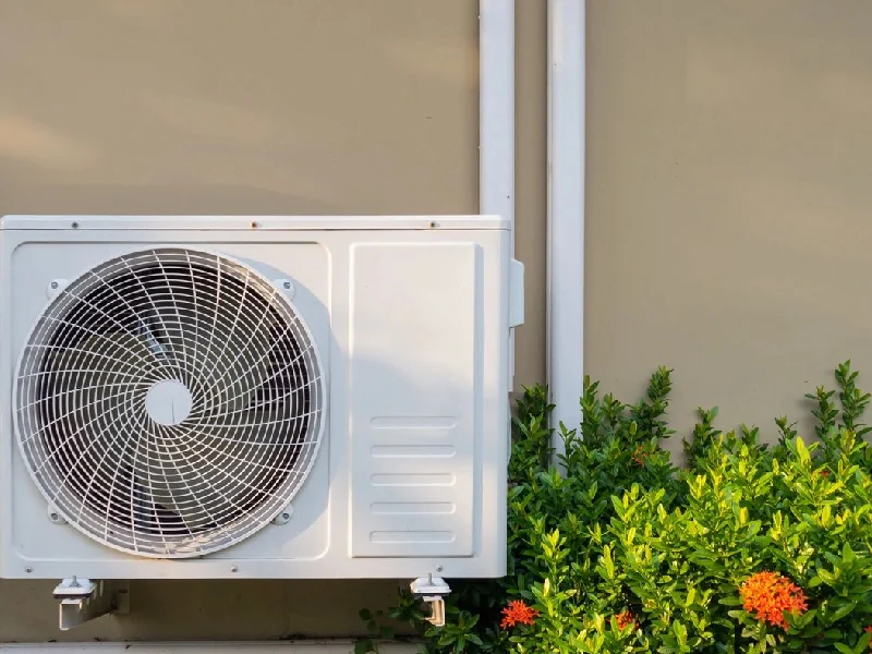 A white air conditioner sitting outside of a house.